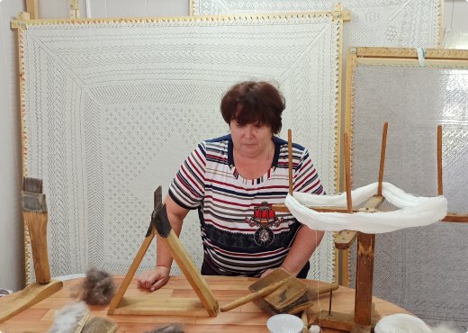 Мастерица за растянутым на раме пуховым платком
